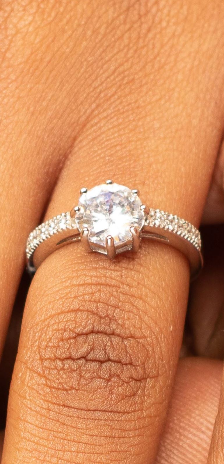 Solitaire ring with pavé shoulders on a finger