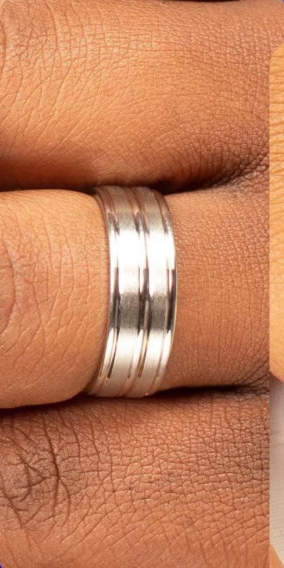 Brushed sterling silver wedding band with grooves on a finger